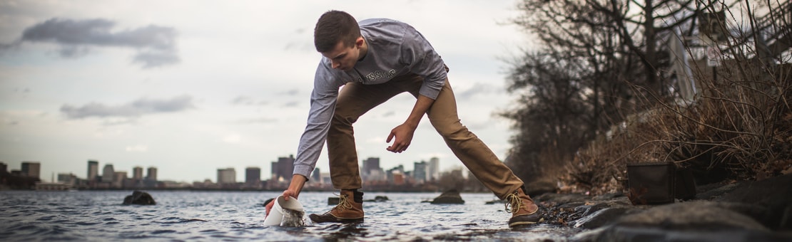 Student taking water sample from Charles River